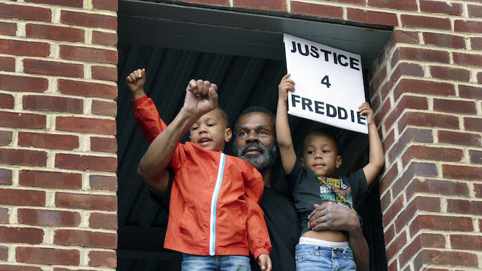 Family holds signs that read justice for Freddie!