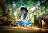 Woman enjoy nature resting relax after reading book in garden public park in the light of morning ch...