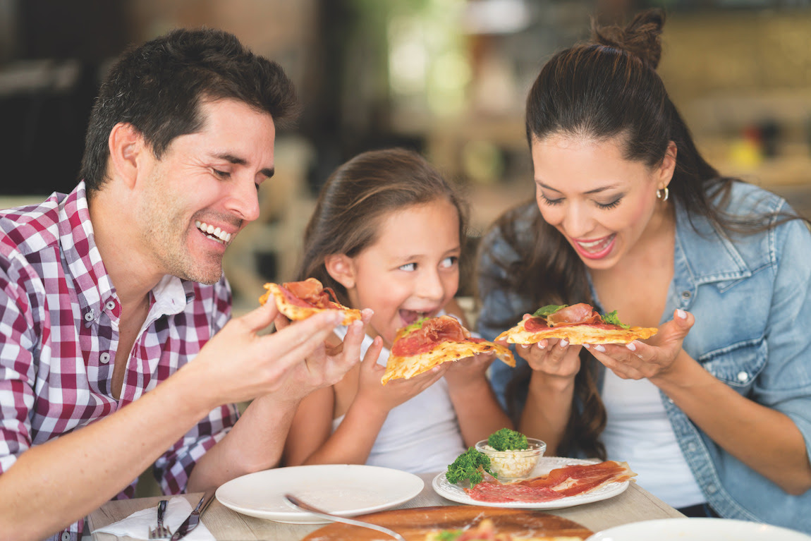 Happy family eating pizza at a restaurant