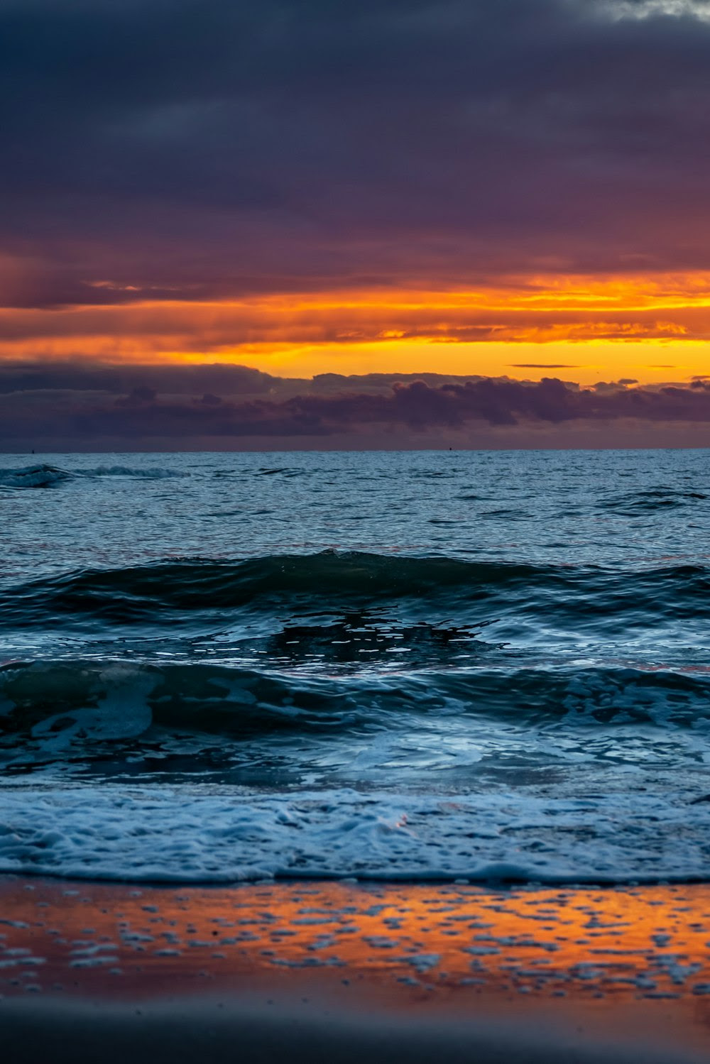 ocean waves under orange sky during sunset