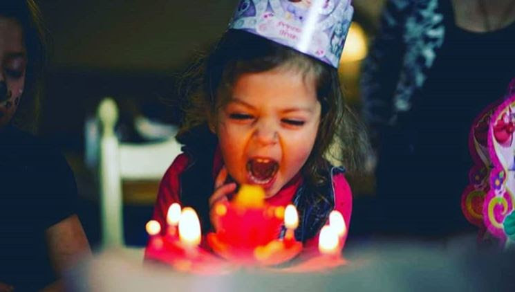 kid blowing out birthday cake candles