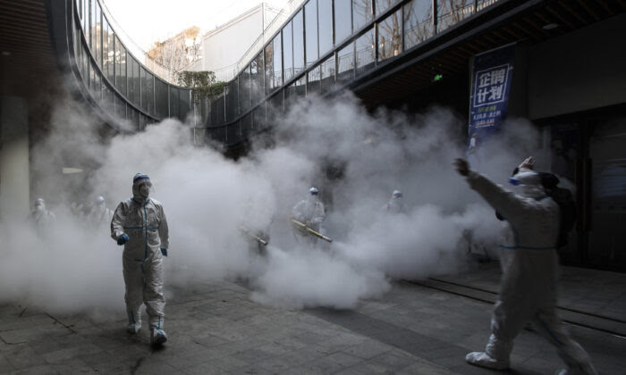 Staff members wearing personal protective equipment (PPE) spray disinfectant outside a shopping mall in Xi'an, China, on Jan. 11, 2022. (STR/AFP via Getty Images)