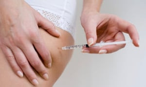 Woman self- administering insulin with a hypodermic syringe