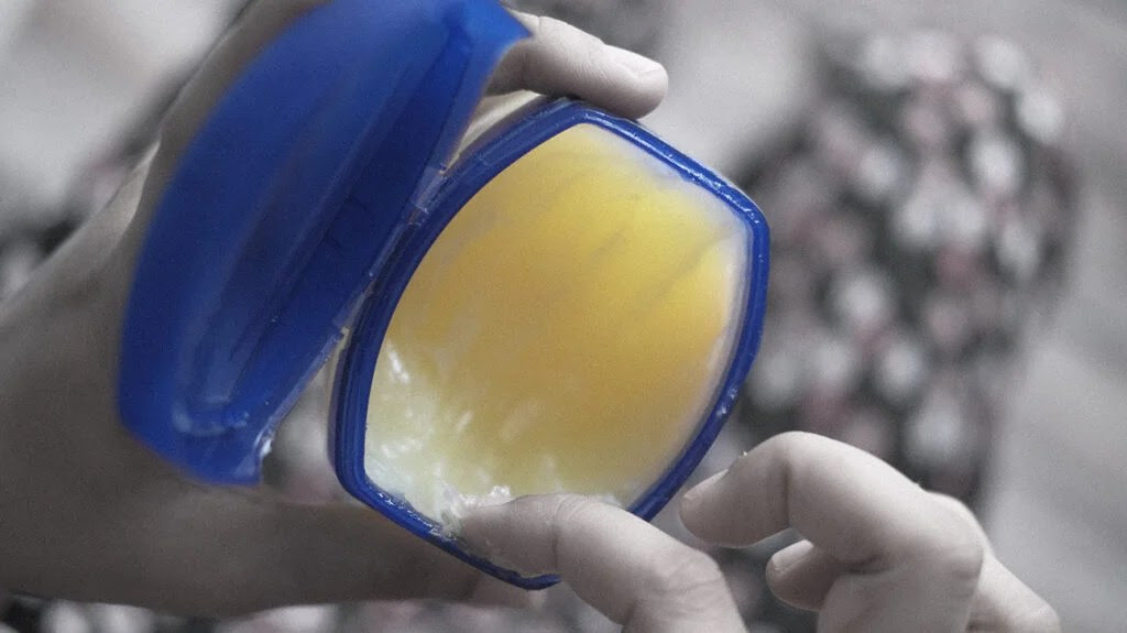 Close up of Vaseline pot and a hand.