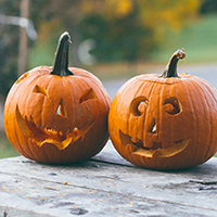 Two carved pumpkings sitting on a table.