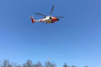 Rescue basket hanging from Coast Guard helicopter