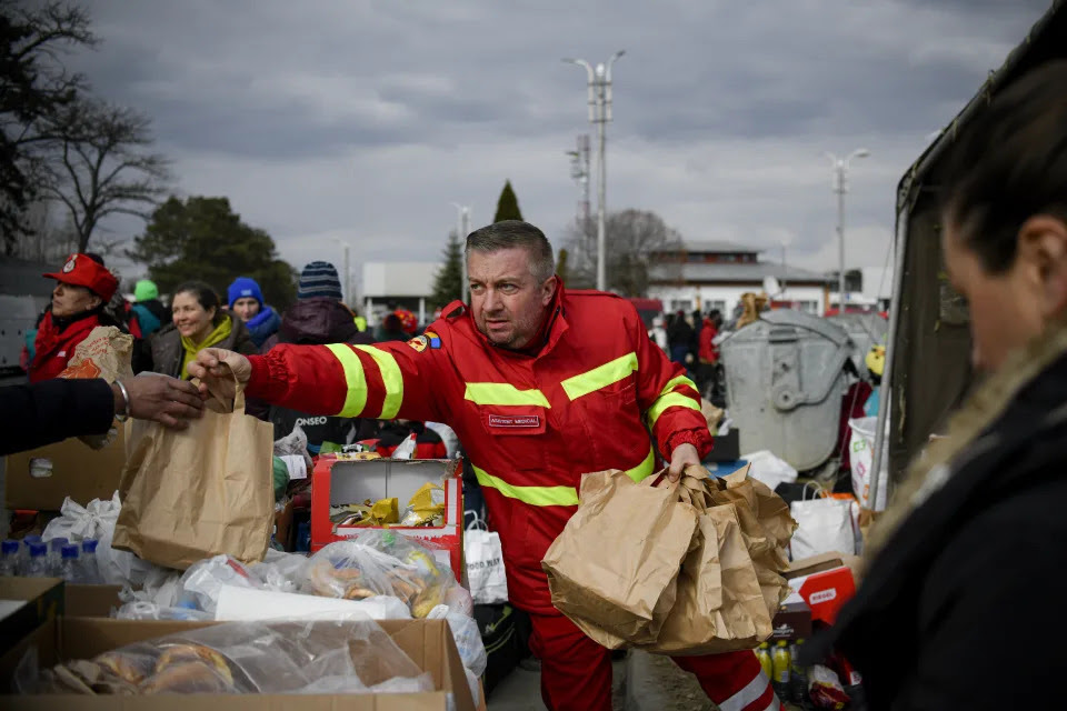 An emergency worker hands out bags of food.