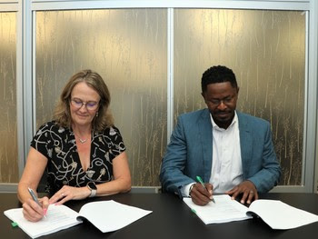 Two people behind a desk signing papers