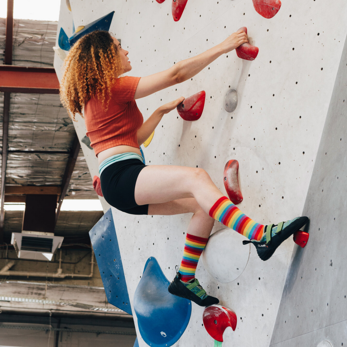 Person on rock climbing wall wearing rainbow socks 