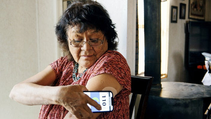 Senior woman, checking her blood glucose level with a smartphone application.