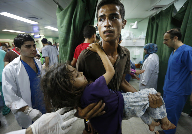 A Palestinian youth carries a child, wounded in an Israeli strike on a compound housing a U.N. school in Beit Hanoun, in the northern Gaza Strip, into the em...