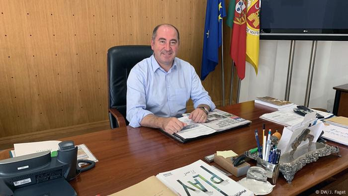 Homem de meia-idade sorridente, sentado a mesa de trabalho Homem de meia-idade sorridente, sentado a mesa de trabalho