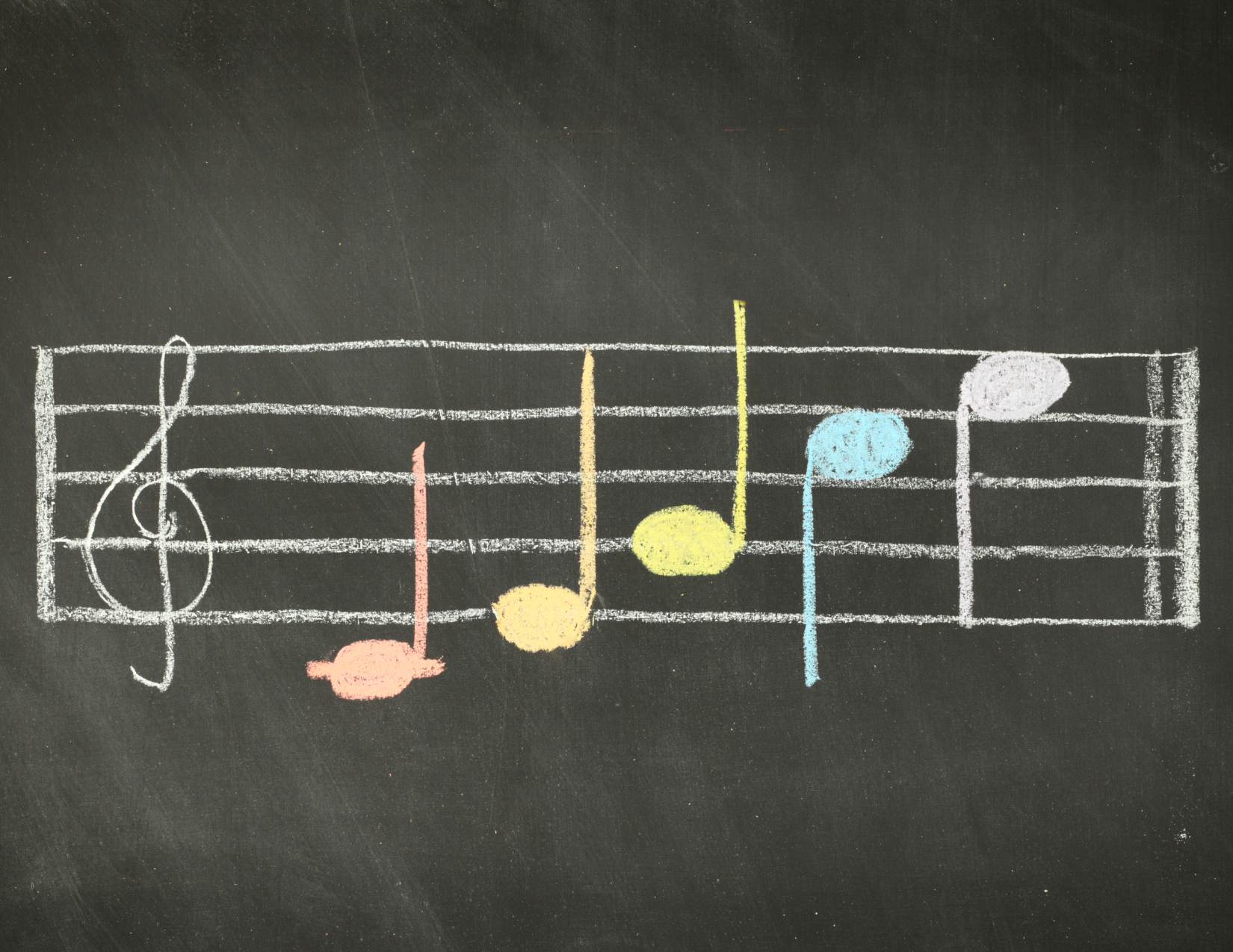 Chalkboard background with a white music scale and rainbow notes going up the scale.