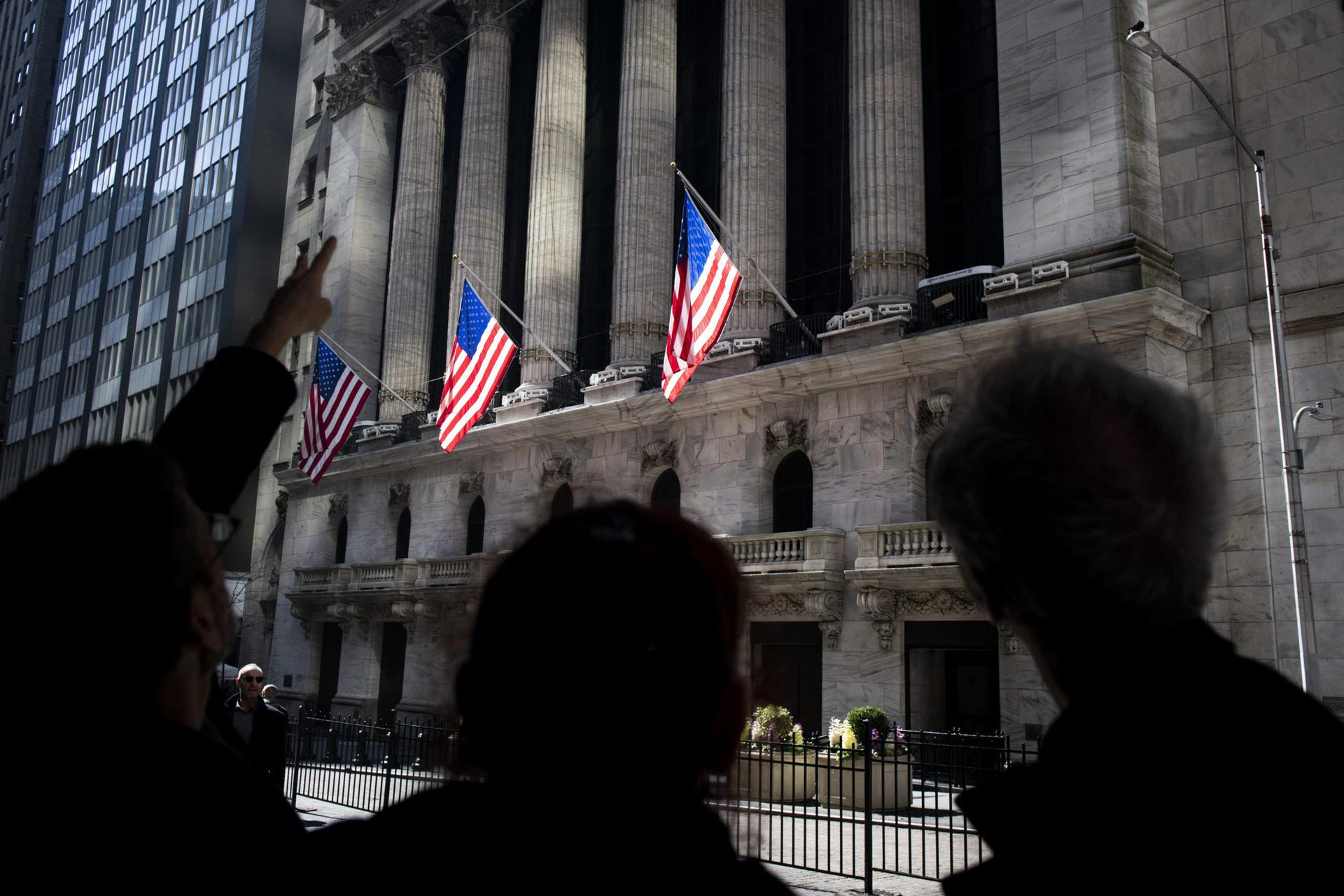 People pointing at Wall Street buildings