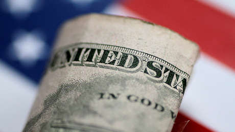 Un billete de dólar plegado frente a la bandera nacional de EE.UU.