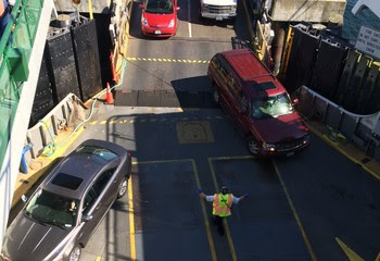 Person in safety vest directing vehicles onto the car deck of a ferry