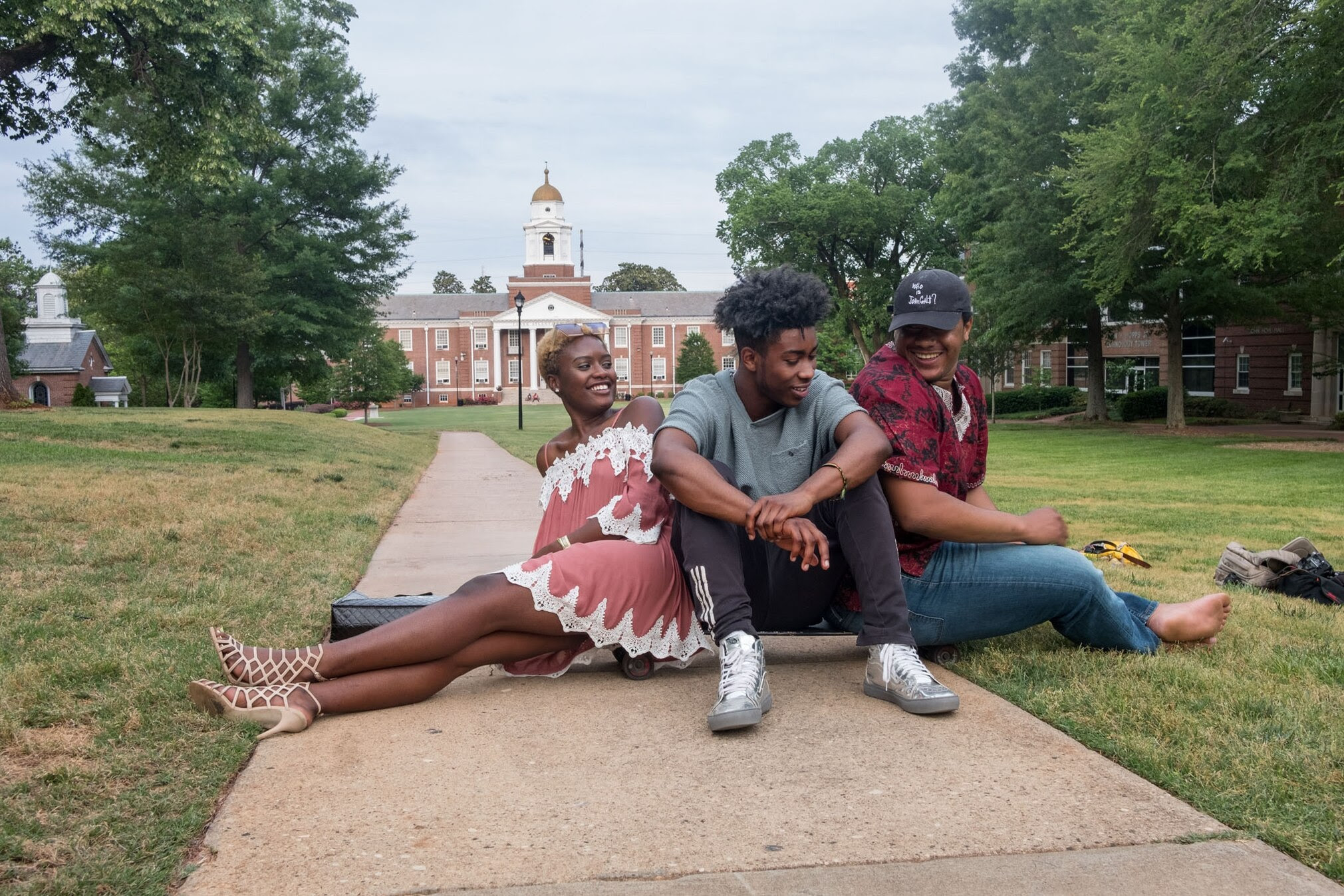 three black students 2 men and one woman sitting on a campus lawn