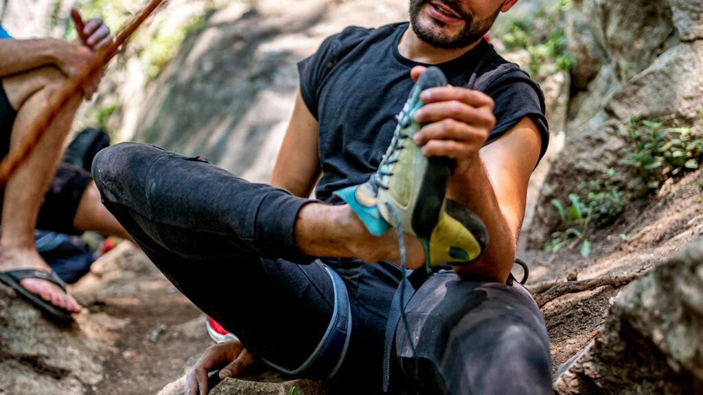 A hiker sitting and holding their foot.