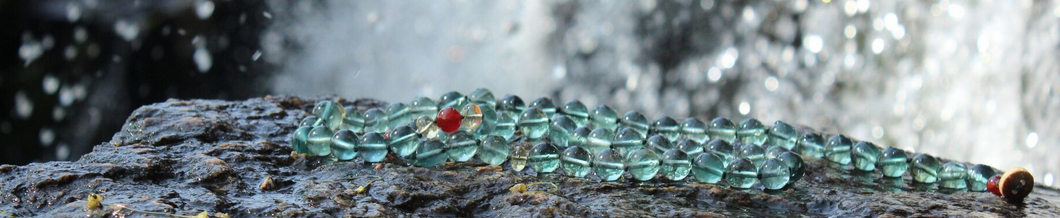 Blue-Green Fluorite gemstone necklace in front of waterfall