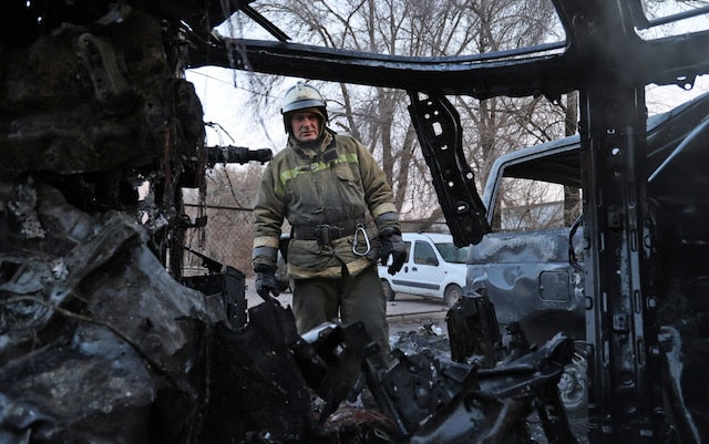 A firefighter examines a burned car after a shelling by Ukrainian forces in Donetsk.