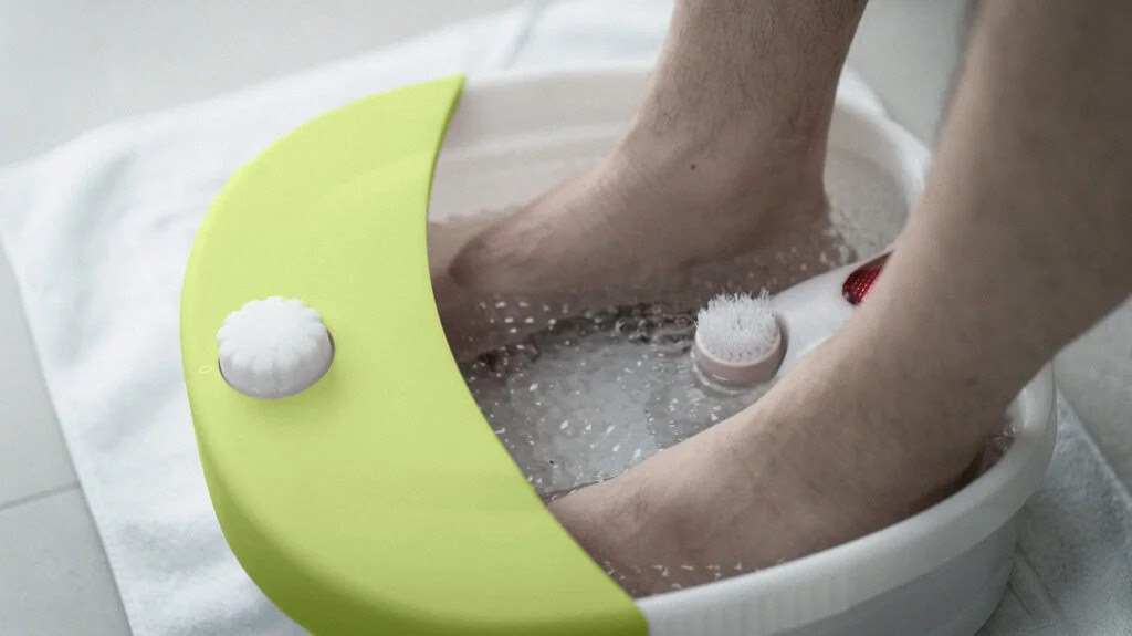 a person soaks their feet in a foot spa - one of many home remedies for burning feet