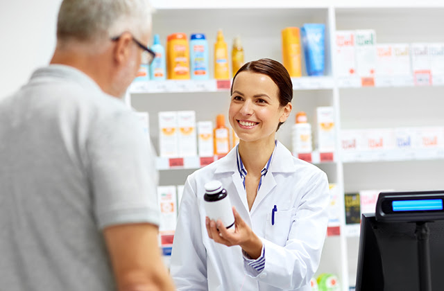 Pharmacist handling a bottle of meds to customer