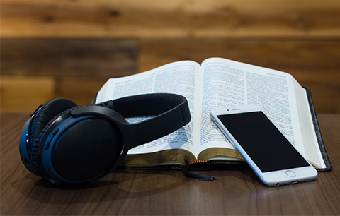 Headphones, a cellphone, and an open Bible