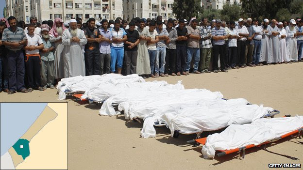 Palestinian mourners pray in front of the bodies of ten members of the al-Astal family killed in a strike on their home