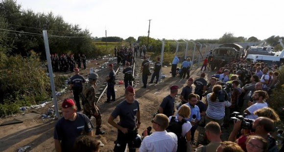 Journalists watch as Hungarian police officers seal off the border with Serbia, near the Hungarian migrant collection point in Roszke, Hungary, September 14, 2015, .  REUTERS/Laszlo Balogh
