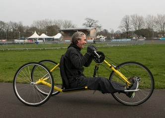 Picture of a person using an accessible bicycle to cycle around a park