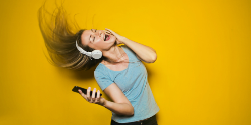 photo of woman listening to music with headphone on and singing along