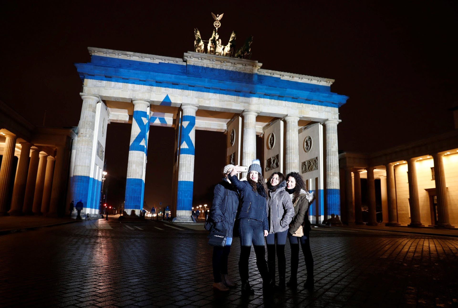 Women pose for a selfie in front of the Brandenburg Gate with the Israeli flag projected onto in Berlin to pay tribute to the victims of a ramming attack in Jerusalem, January 9, 2017.
