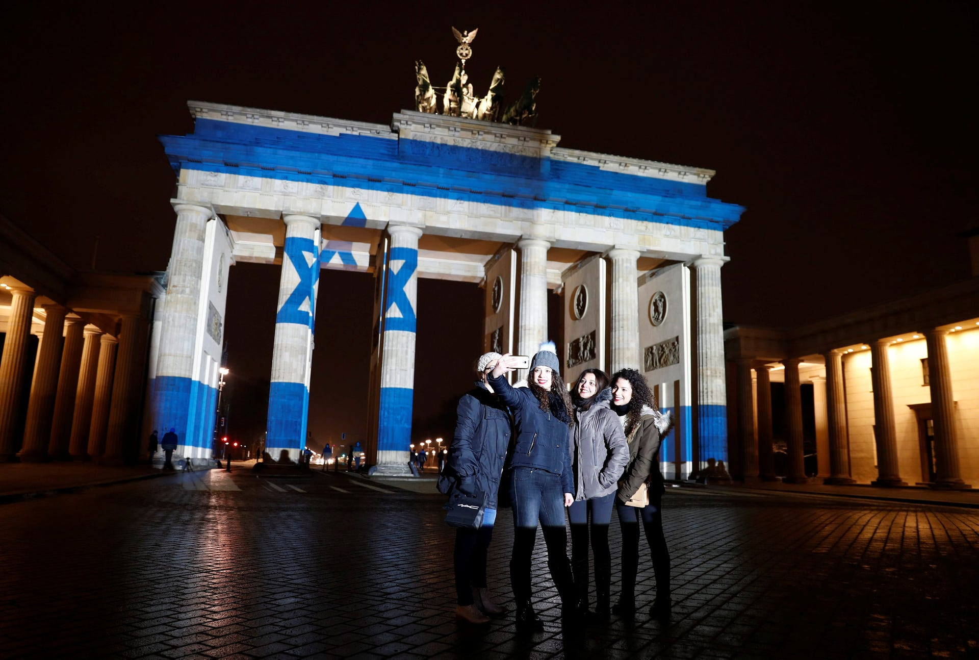 Women pose for a selfie in front of the Brandenburg Gate with the Israeli flag projected onto in Berlin to pay tribute to the victims of a ramming attack in Jerusalem, January 9, 2017.