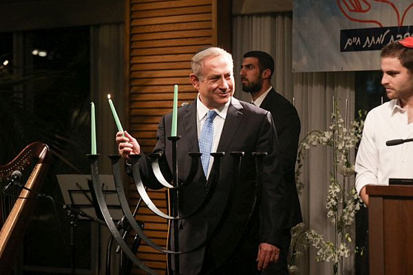 Israeli Prime Minister Benjamin Netanyahu lights the Chanukah candles on the first night of the Jewish holiday at Ronit's farm, outside Tel Aviv on December 24, 2016.