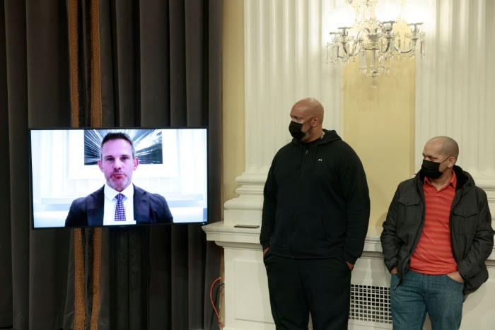 U.S. Capitol Police officers Sgt. Aquilino Gonell and Harry Dunn listen as Rep. Adam Kinzinger speaks remotely during a business meeting with the select committee on Capitol Hill.