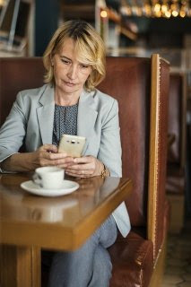 Woman Reading on Phone at Coffee Shop