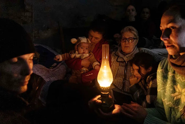 People sit around an oil lamp in a bomb shelter in Mariupol. 
