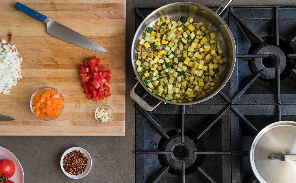 How to cook with stainless steel: chopped vegetables on a cutting board and in a stainless steel pan