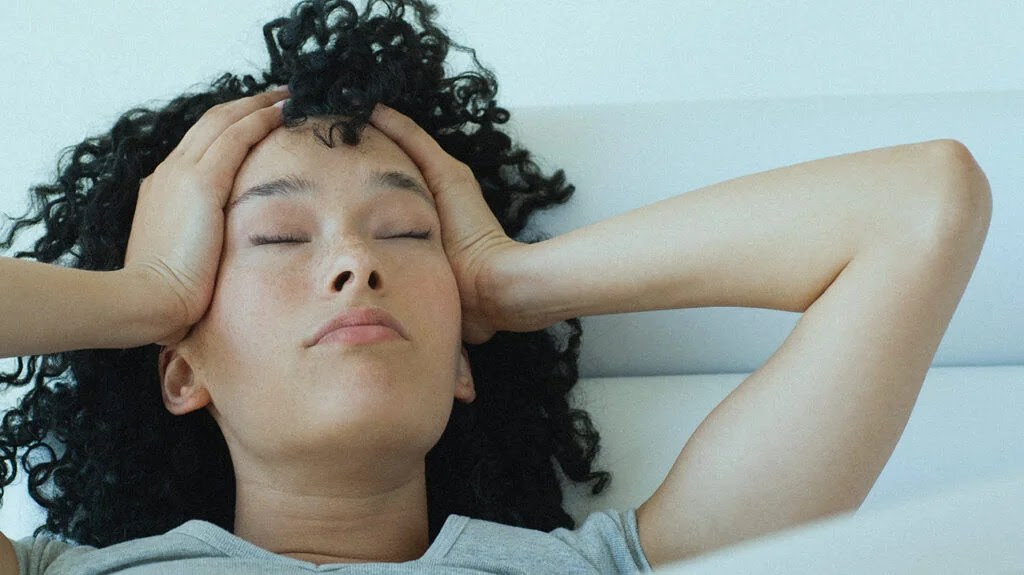 A woman with painful scalp when the hair moves touches her head.