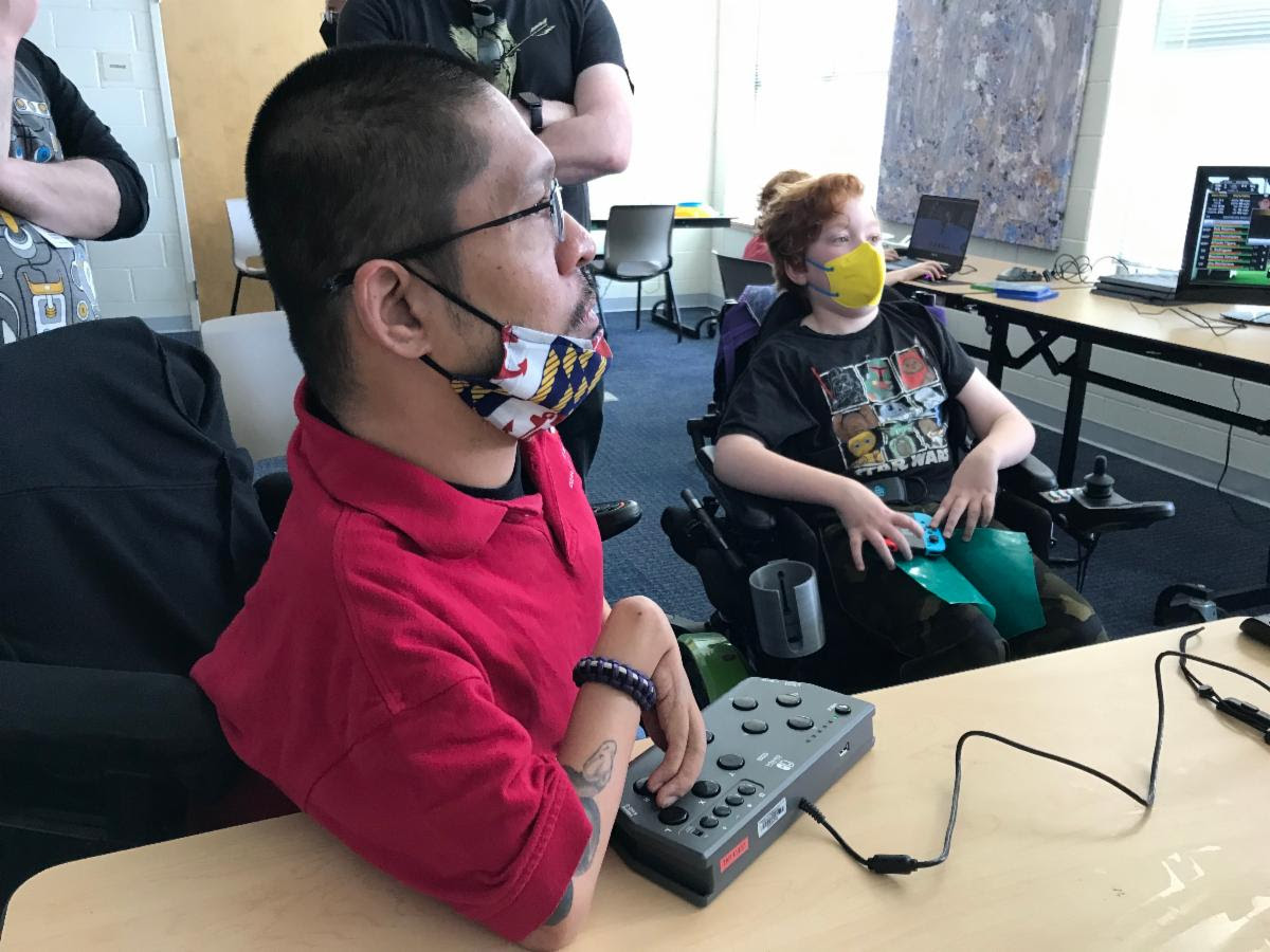 Two gamers using adapted controllers