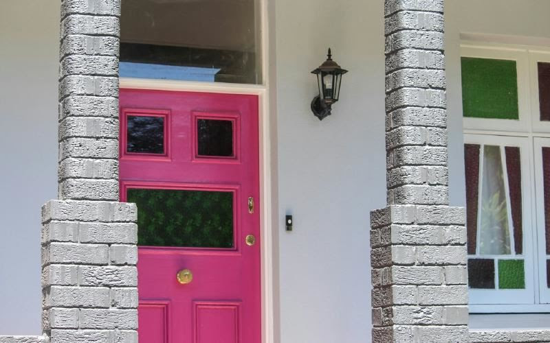 A pink door with a white wall Description automatically generated