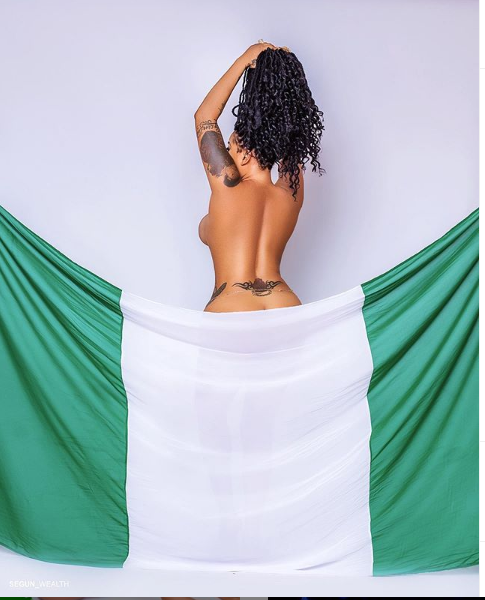 Toyin Lawani barely covers her body with a green and white piece of material to mark Nigeria