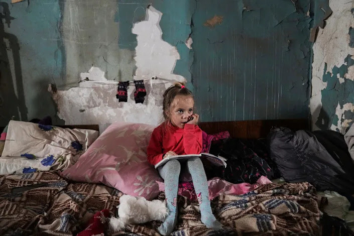 A little girl sits in an improvised bomb shelter in Mariupol. 