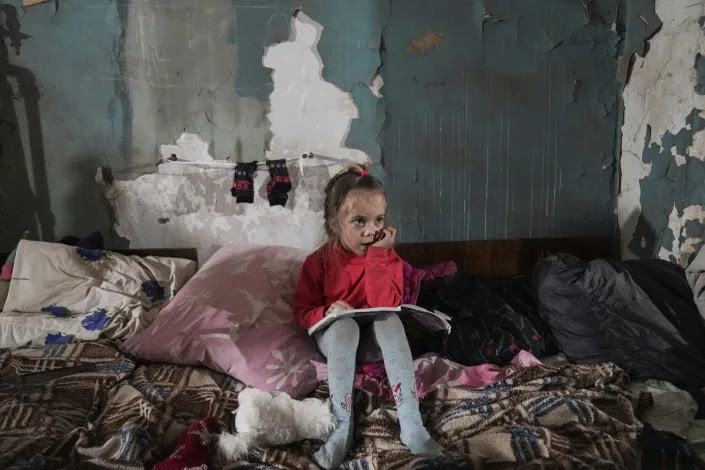 A little girl sits in an improvised bomb shelter in Mariupol. 