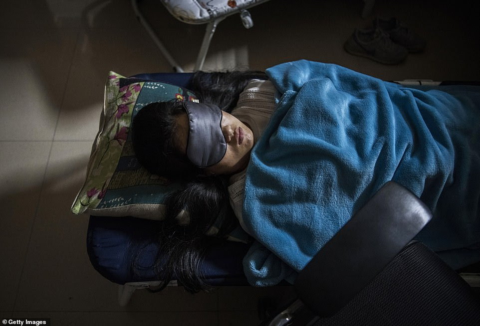 A Huawei employee sleeps in her cubicle in the research and development department offices after lunch