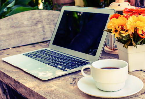 a cup of coffee and laptop on wood floor with flower_ vintage style