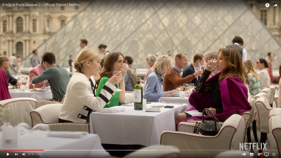 Emily in Paris enjoying the finer things in Paris like this Malartic Grand Cru Classé Blanc in front of the Louvre Museum pyramid
