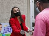 First-term U.S. Rep. Alexandria Ocasio-Cortez, D-New York, left, hands out leaflets explaining how to vote early or by absentee ballot to a pedestrian at the Parkchester subway station in the Bronx borough of New York, Monday, June 15, 2020, in New York. Ocasio-Cortez is running against challenger and former journalist Michelle Caruso-Cabrera and others in New York&#39;s June 23 primary. (AP Photo/Kathy Willens)