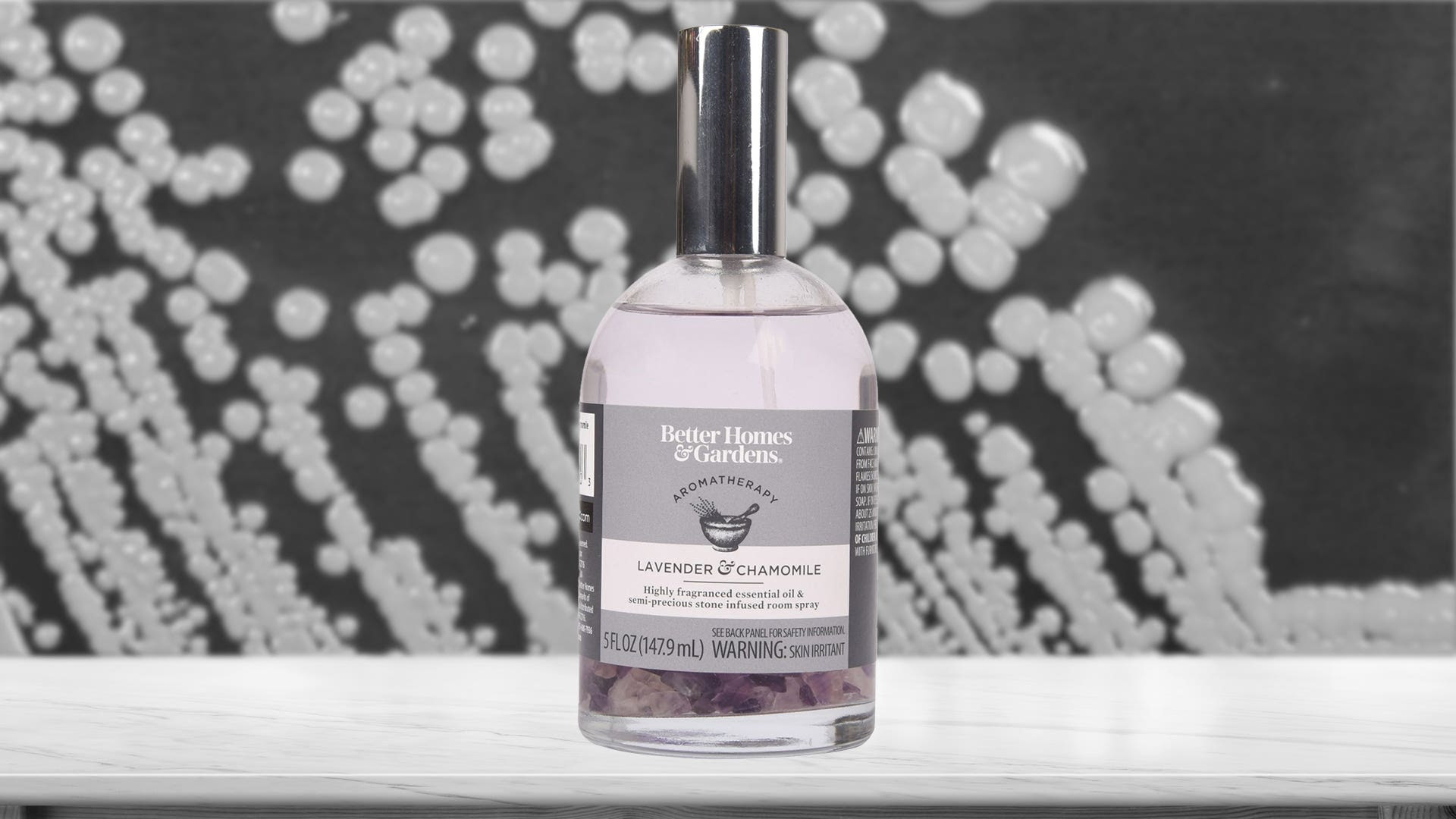 A bottle of Better Homes & Gardens Lavender & Chamomile with Gemstones over a photo of Burkholderia pseudomallei