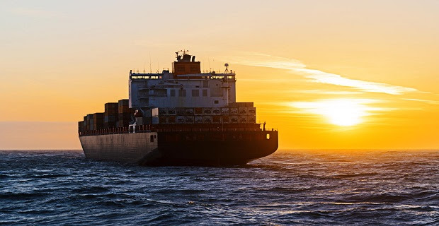 Container ship heading towards sunset